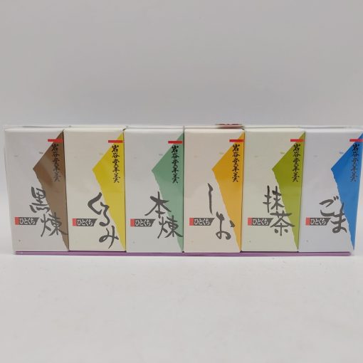Confezione di yokan Kaishindo con sei gusti tradizionali: sei scatole rettangolari allineate, ognuna con un colore e un gusto diverso. Da sinistra a destra: marrone scuro (zucchero di canna nero - kuroneri), giallo (noci - kurumi), verde scuro (honneri, pasta pura di fagioli azuki), arancione (sale - shio), verde chiaro (matcha, tè verde in polvere) e blu (sesamo - goma). Ogni scatola porta il marchio Kaishindo in caratteri giapponesi e il nome del gusto in verticale. Gli yokan sono dolci tradizionali giapponesi a base di pasta di fagioli azuki, zucchero e agar-agar, con una consistenza liscia e vellutata.