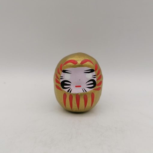Bambola Daruma dorata tradizionale giapponese, vista frontale con dettagli del volto stilizzato