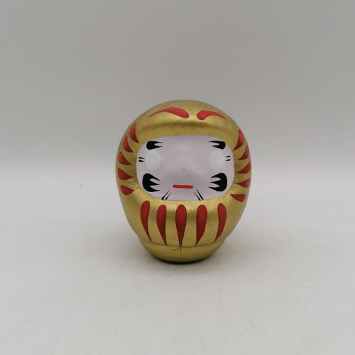 Bambola Daruma dorata tradizionale giapponese, vista frontale con dettagli del volto stilizzato