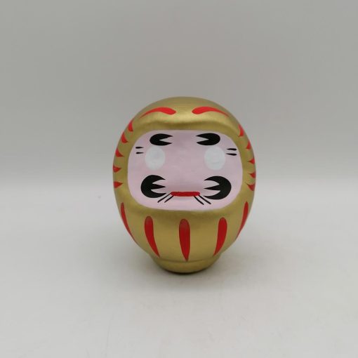 Bambola Daruma dorata tradizionale giapponese, vista frontale con dettagli del volto stilizzato