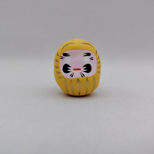 Bambola Daruma gialla tradizionale giapponese, vista frontale con dettagli del volto stilizzato e corpo tondeggiante