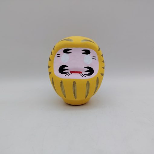 Bambola Daruma gialla tradizionale giapponese, vista frontale con dettagli del volto stilizzato e corpo tondeggiante