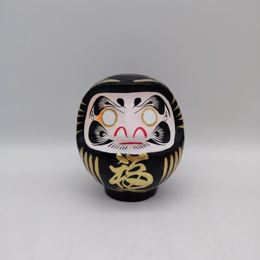 Bambola Daruma nera tradizionale giapponese, vista frontale con dettagli del volto stilizzato e corpo tondeggiante