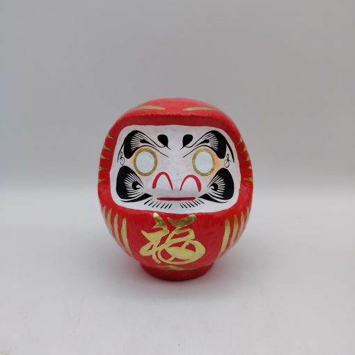 Bambola Daruma rossa tradizionale giapponese, vista frontale con dettagli del volto stilizzato e corpo tondeggiante