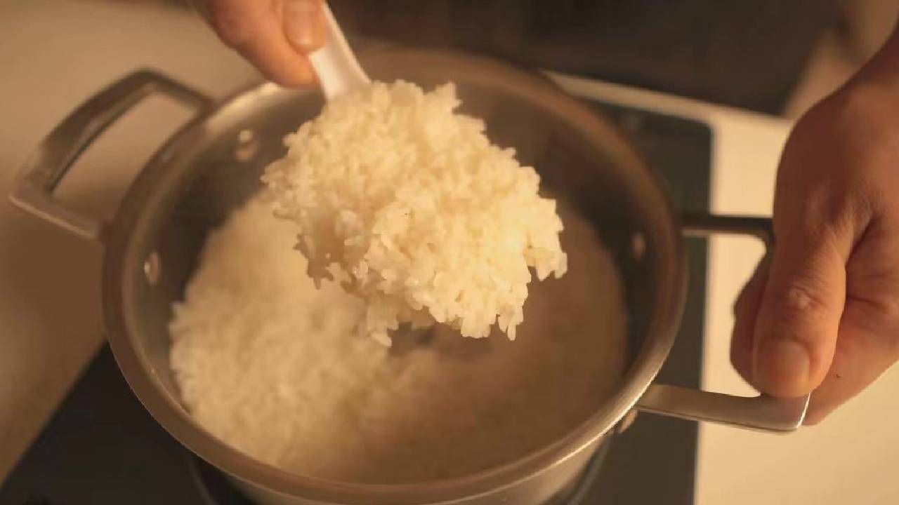 Mani esperte mescolano il riso cotto in una pentola, fase fondamentale per preparare gli onigiri tradizionali.